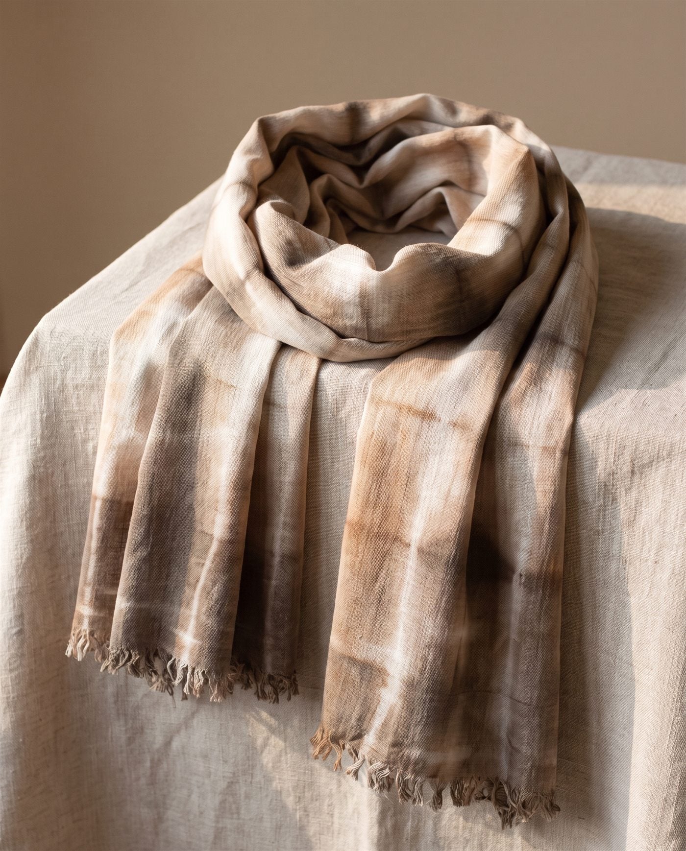 Foulard de bambula de algodón teñido con shibori en rectángulos marrones, doblado sobre lino natural