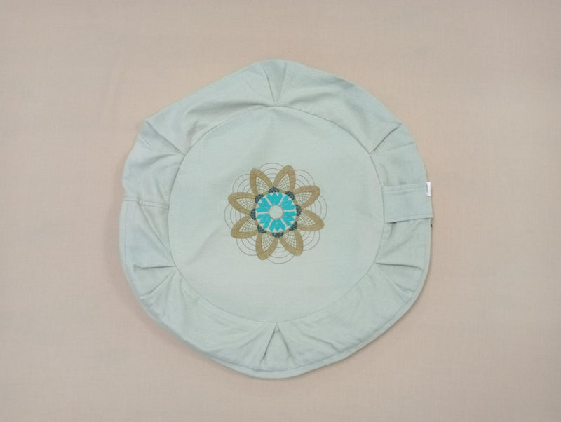 Funda de zafu verde agua con una flor bordada en turquesa y ocre